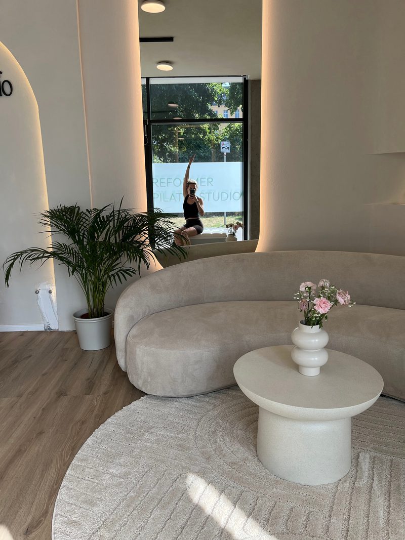 Lounge-Bereich mit Couch, Blumen und Blick durch die Glasfront