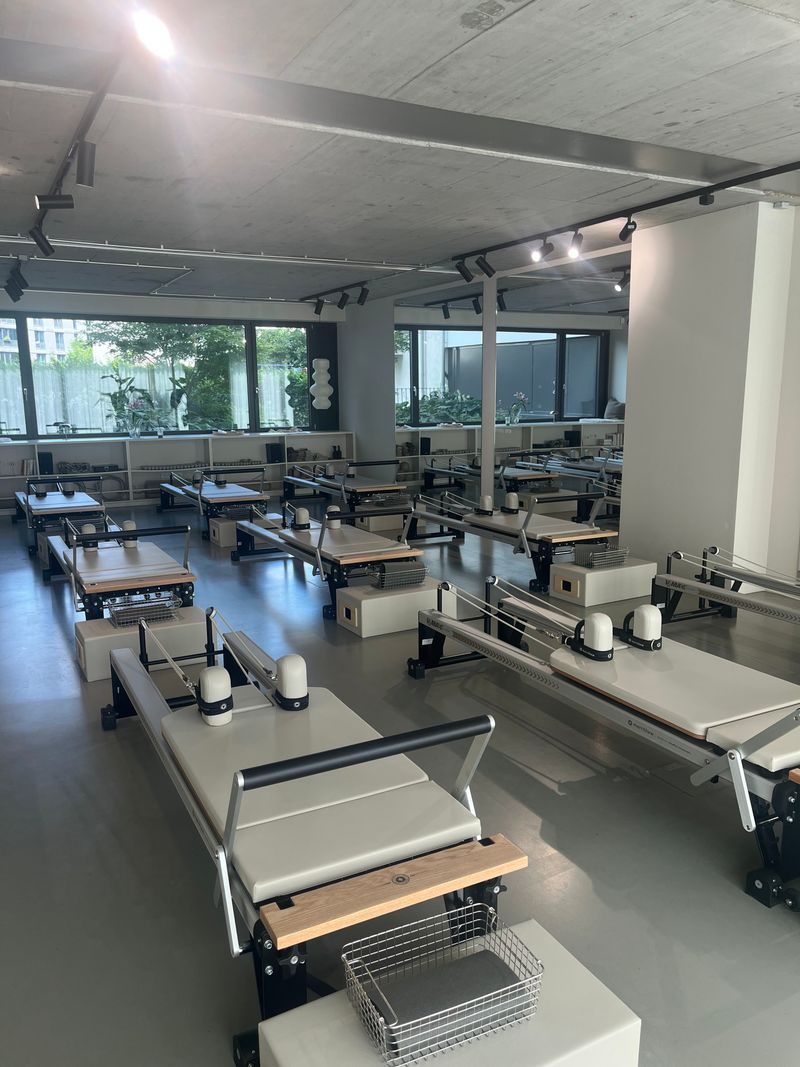 The Frame Berlin: Blick über die Merrithew Reformer mit Spiegelwand und Fensterfronten